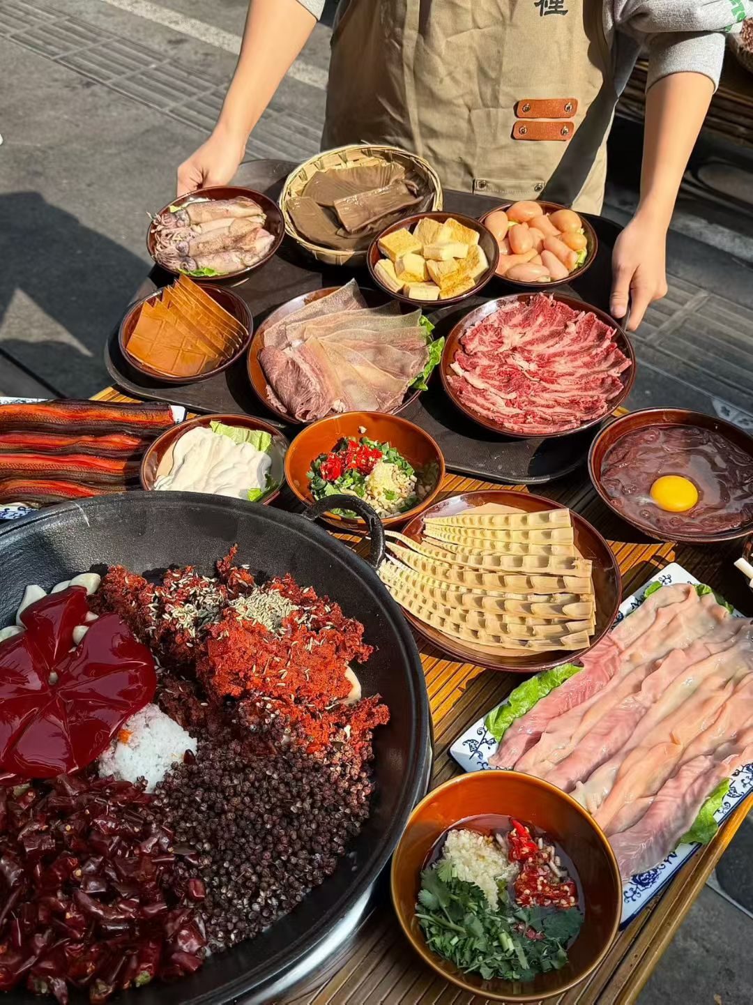 满桌涮品俯拍：鲜毛肚、嫩牛肉、黄喉、鸭肠，中间一口红亮的干锅底