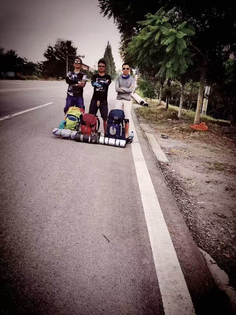 2016 年徒步路上，三个人背着登山包站在公路边